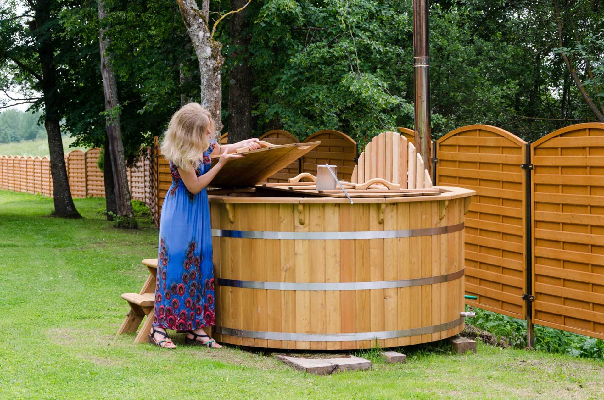 Frau im Garten deckt Badefass, Hot tube ab